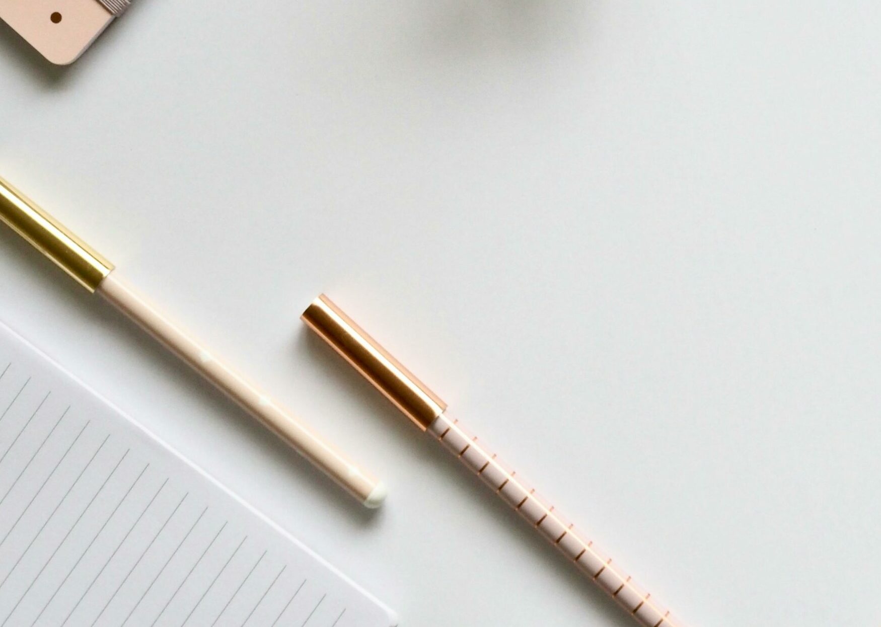 Stylish rose gold themed flatlay featuring office supplies and a smartwatch on a white background.